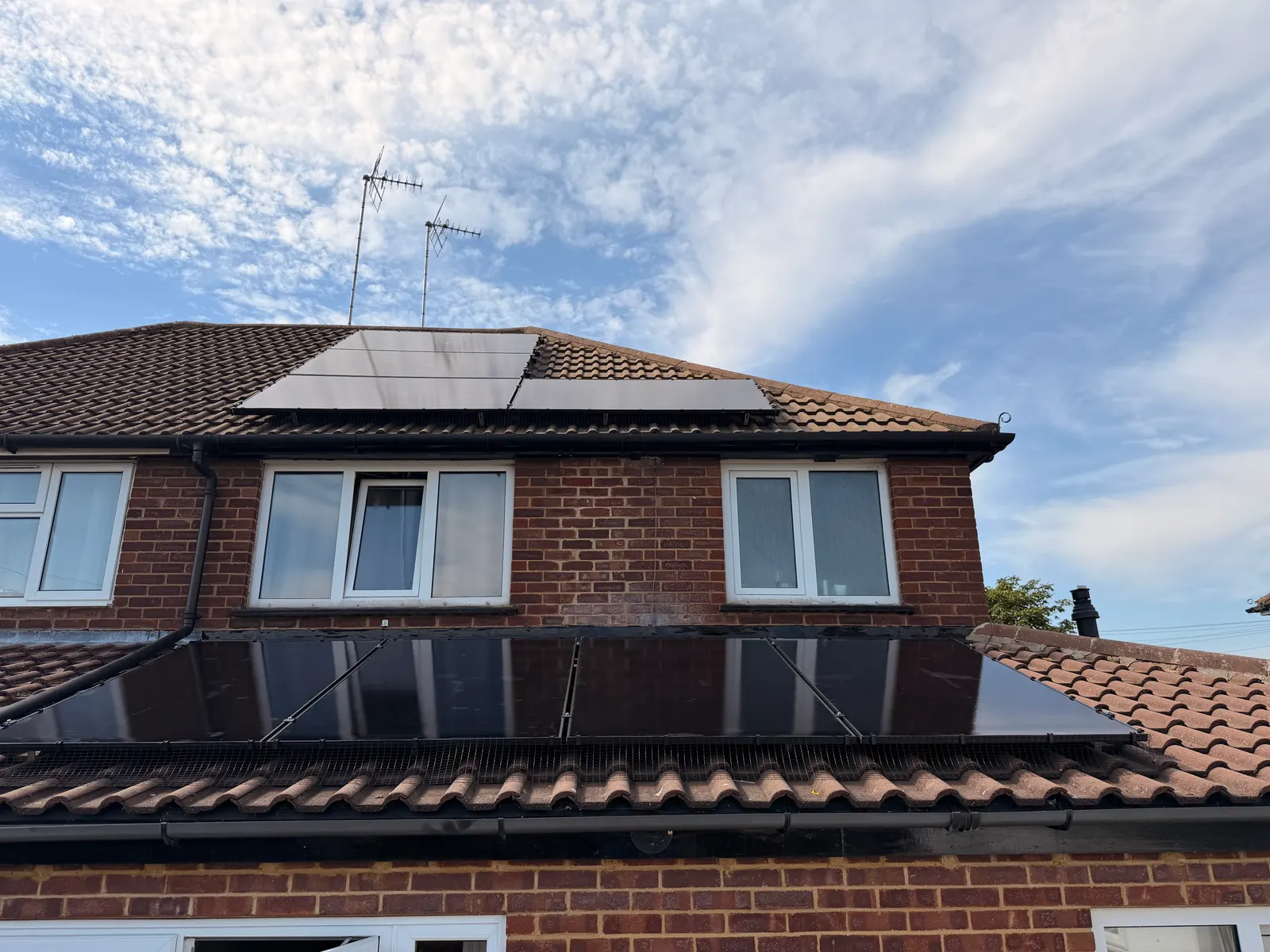 All-black solar panels on two roof levels of a Leighton Buzzard semi